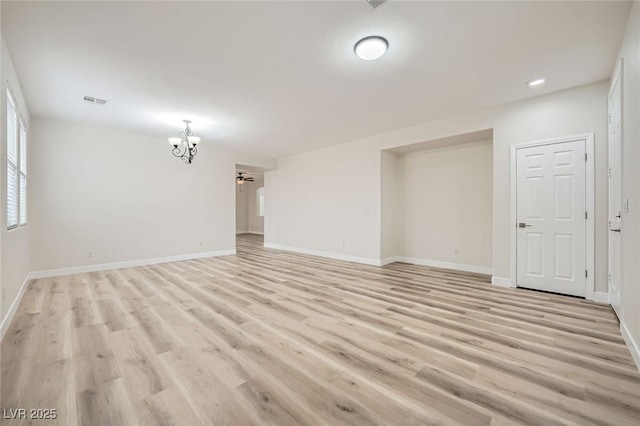 empty room featuring baseboards, visible vents, and light wood finished floors