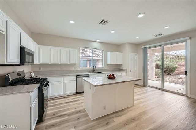 kitchen with appliances with stainless steel finishes, a sink, visible vents, and white cabinets