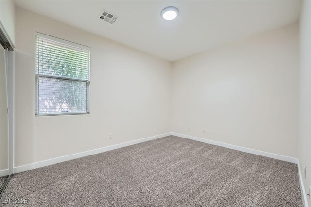 carpeted empty room with visible vents and baseboards