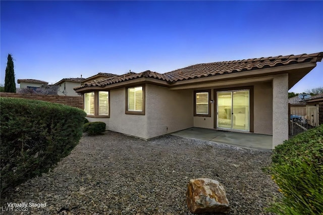 rear view of property featuring a tile roof, fence, a patio, and stucco siding