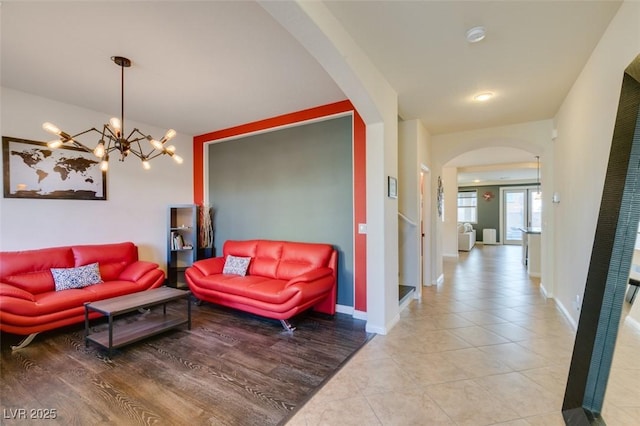 tiled living area featuring baseboards and arched walkways