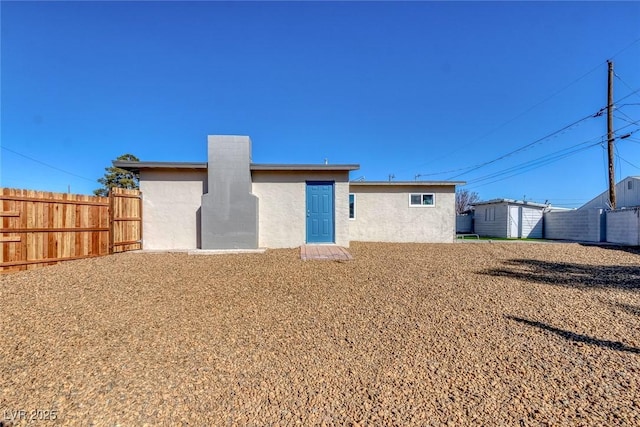 back of house featuring a storage shed, fence, an outbuilding, and stucco siding