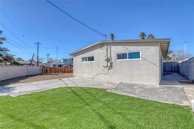 rear view of house featuring a fenced backyard, a lawn, a patio, and stucco siding