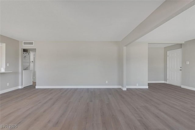 spare room with wood finished floors, visible vents, and baseboards