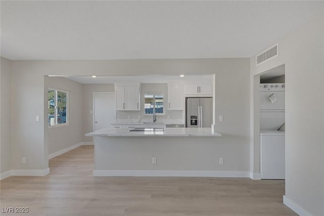 kitchen featuring stainless steel fridge, visible vents, white cabinets, light countertops, and a wealth of natural light