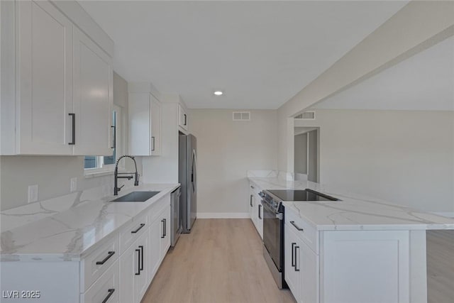 kitchen with stainless steel appliances, visible vents, a sink, and a peninsula