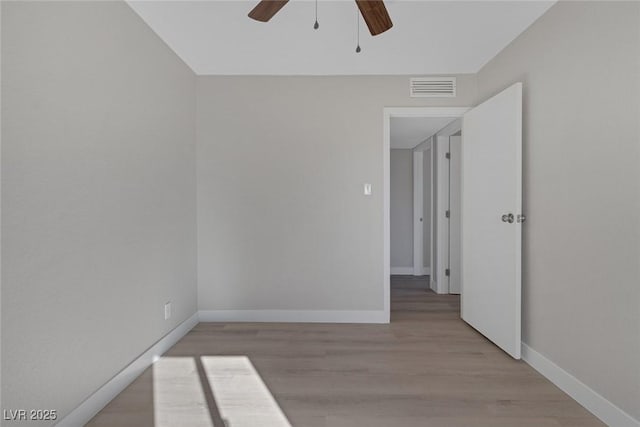 unfurnished room with light wood-type flooring, visible vents, ceiling fan, and baseboards