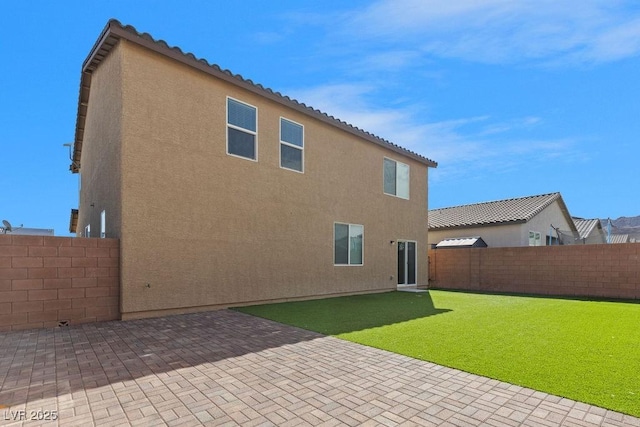 back of property featuring a tile roof, a yard, stucco siding, a patio area, and a fenced backyard