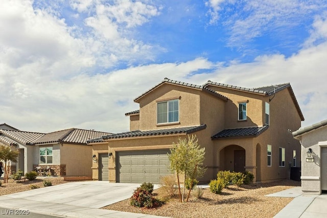 mediterranean / spanish house with a garage, driveway, a tiled roof, and stucco siding