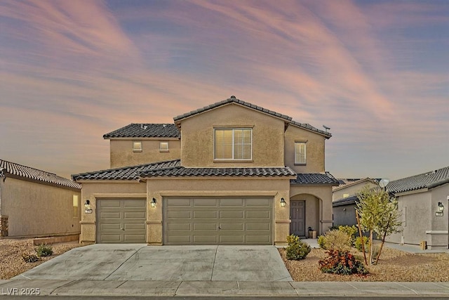 mediterranean / spanish home with a garage, driveway, a tile roof, and stucco siding