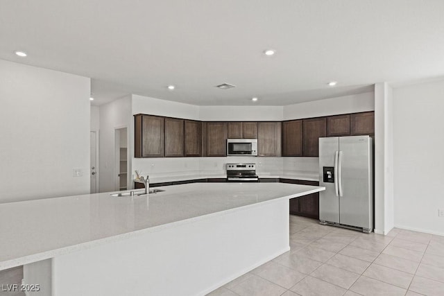 kitchen featuring stainless steel appliances, light countertops, a sink, and dark brown cabinetry