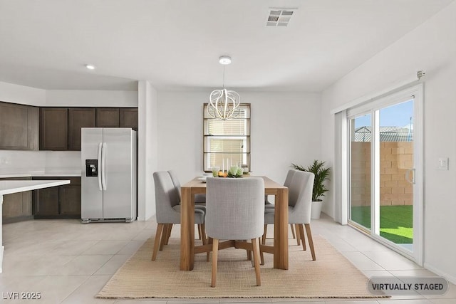 dining area featuring light tile patterned floors, visible vents, and an inviting chandelier