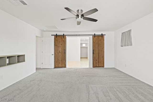 empty room with a barn door, carpet flooring, and visible vents