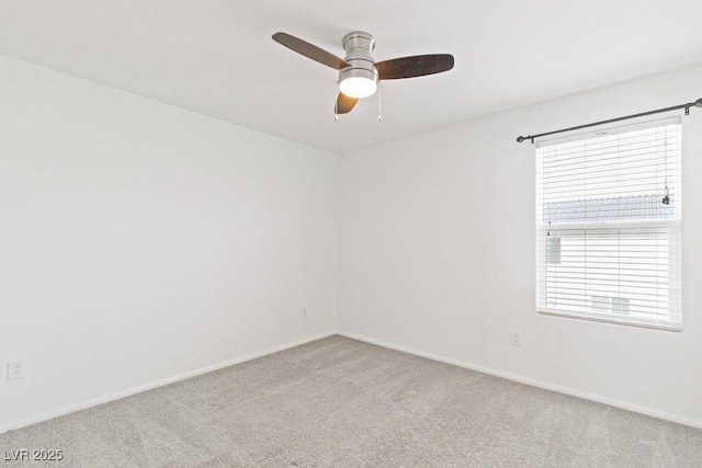 spare room with a ceiling fan, light colored carpet, and baseboards