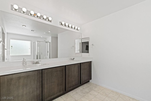 full bath featuring double vanity, a shower stall, visible vents, and a sink