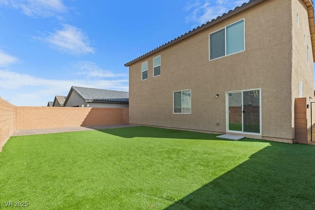 rear view of property with a lawn, a fenced backyard, and stucco siding