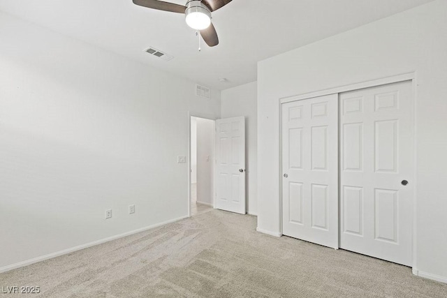 unfurnished bedroom featuring baseboards, a closet, visible vents, and light colored carpet