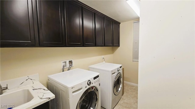 laundry room featuring light tile patterned floors, cabinet space, a sink, independent washer and dryer, and baseboards