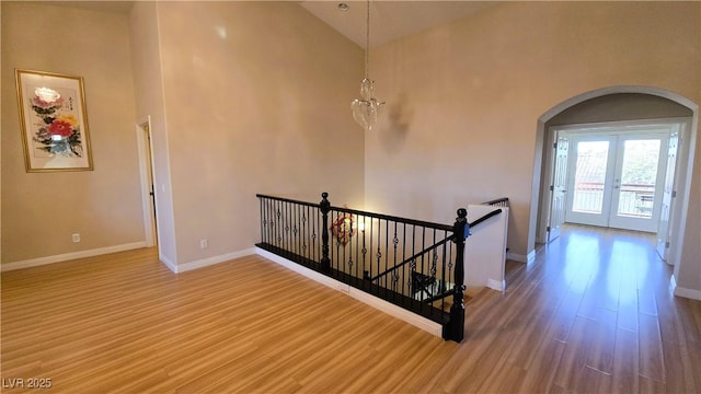 hall with arched walkways, wood finished floors, an upstairs landing, and baseboards