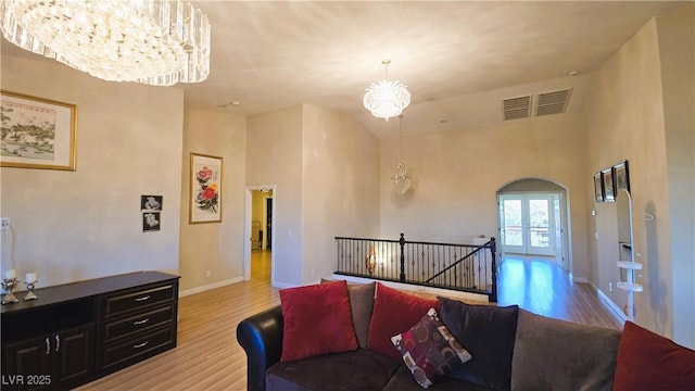 living room featuring french doors, visible vents, wood finished floors, a chandelier, and baseboards