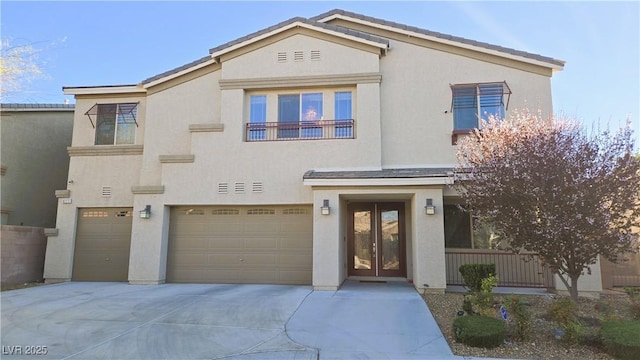 view of front of house featuring a garage, driveway, french doors, and stucco siding