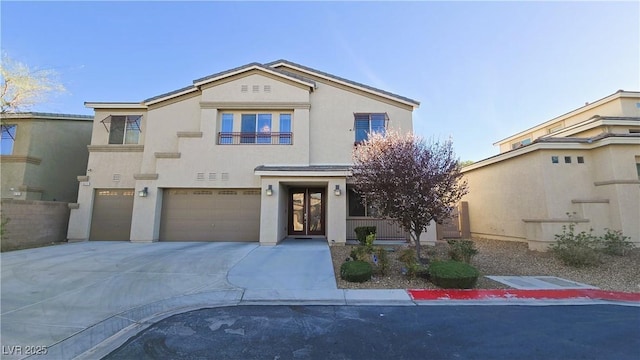 view of front of home with a garage, concrete driveway, and stucco siding