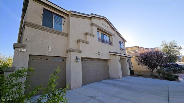 view of front of house with a garage, concrete driveway, and stucco siding