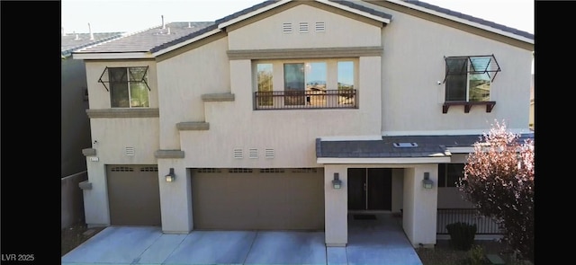 view of front of house featuring driveway, an attached garage, and stucco siding