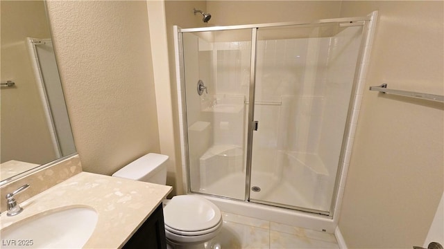 bathroom featuring a textured wall, tile patterned flooring, toilet, vanity, and a shower stall