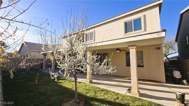 rear view of house featuring a ceiling fan, a patio, fence, a yard, and stucco siding