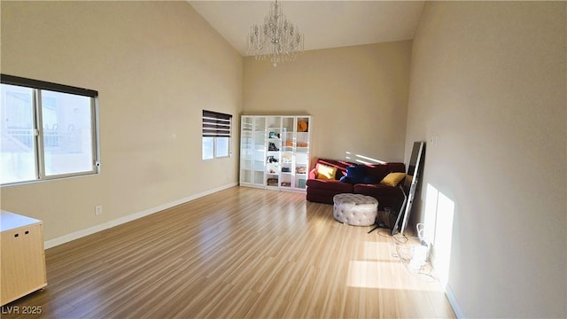 sitting room with high vaulted ceiling, a notable chandelier, baseboards, and wood finished floors