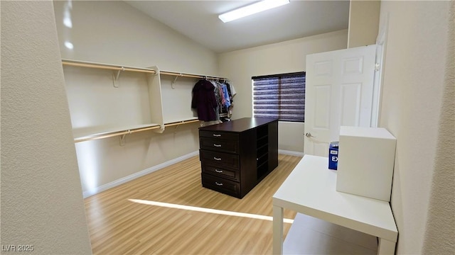 walk in closet featuring light wood finished floors and vaulted ceiling