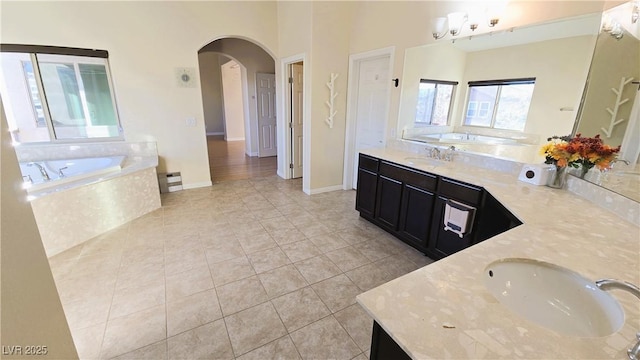 bathroom with vanity, tile patterned flooring, a bath, and baseboards