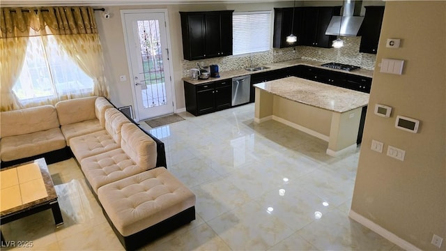 kitchen featuring dark cabinets, open floor plan, ventilation hood, backsplash, and dishwasher