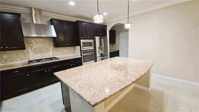 kitchen featuring arched walkways, stainless steel appliances, a kitchen island, wall chimney range hood, and decorative backsplash