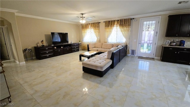 living room featuring ceiling fan, arched walkways, visible vents, baseboards, and ornamental molding