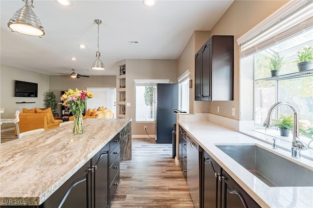 kitchen with a sink, visible vents, a healthy amount of sunlight, dishwasher, and light wood finished floors