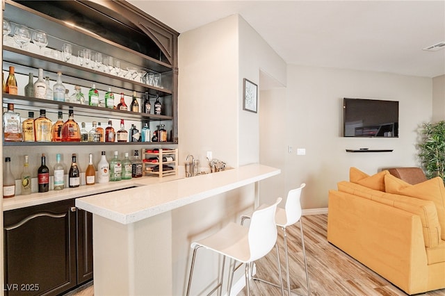 bar featuring visible vents, a dry bar, light wood-style flooring, and baseboards