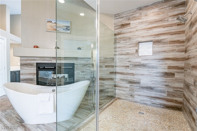 bathroom with a freestanding tub, vanity, a tiled fireplace, and a stall shower