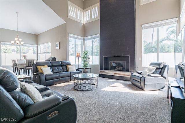 carpeted living area with a fireplace, a high ceiling, and an inviting chandelier