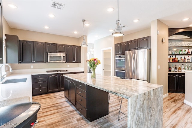 kitchen featuring a sink, visible vents, appliances with stainless steel finishes, a center island, and light wood finished floors