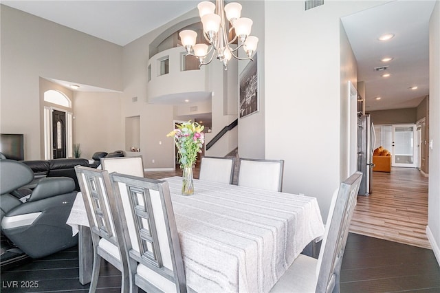 dining room with baseboards, a towering ceiling, dark wood-style floors, a notable chandelier, and recessed lighting