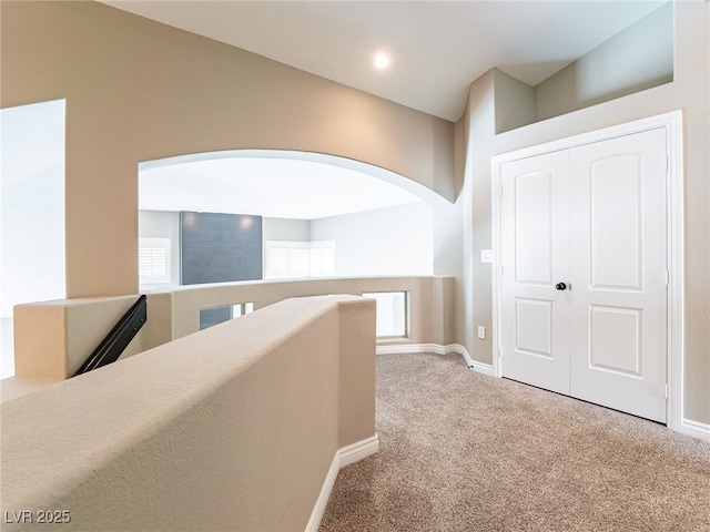 hallway featuring carpet flooring, an upstairs landing, and baseboards