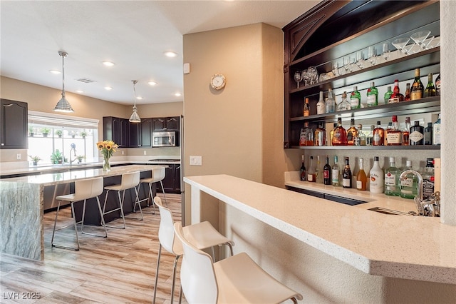 bar featuring recessed lighting, stove, light wood-style floors, stainless steel microwave, and pendant lighting