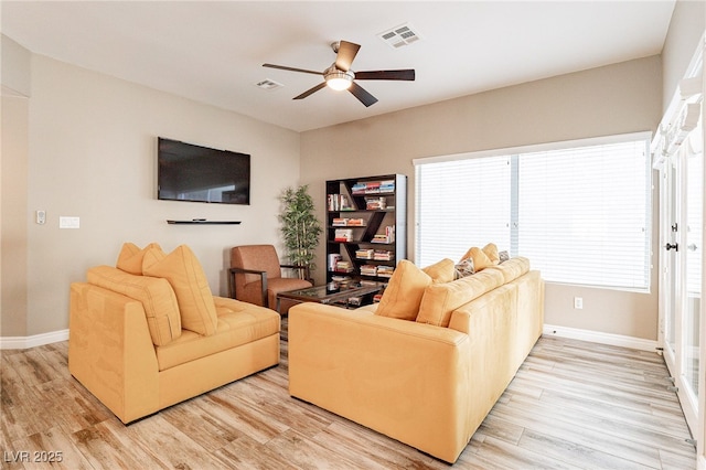 living area featuring light wood-type flooring, visible vents, ceiling fan, and baseboards