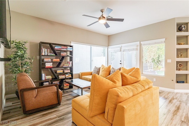 living area with ceiling fan, baseboards, and wood finished floors