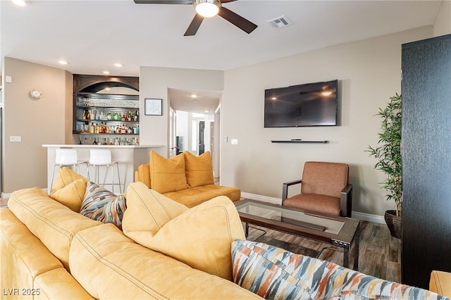 living room featuring visible vents, ceiling fan, a bar, wood finished floors, and baseboards