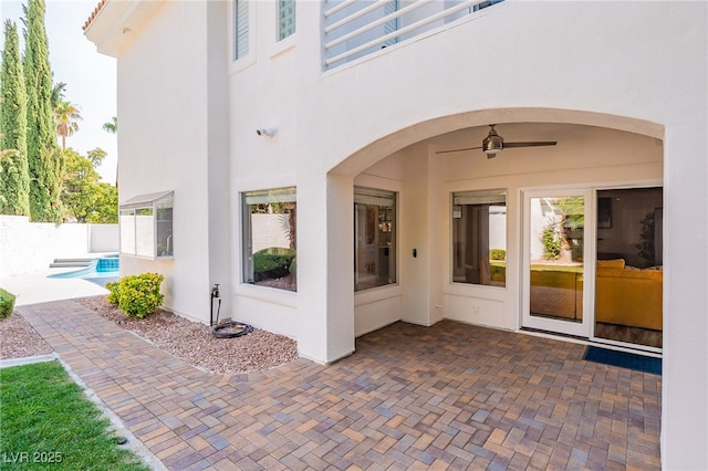 doorway to property featuring a fenced in pool, a patio, ceiling fan, fence, and stucco siding