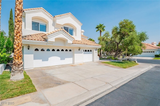 mediterranean / spanish home with a tile roof, driveway, an attached garage, and stucco siding