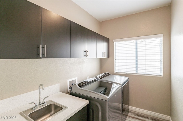 laundry room featuring washer and clothes dryer, cabinet space, a sink, light wood-type flooring, and baseboards